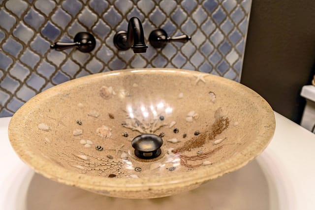 Vessel sink with sea shells and coral embedded within it.