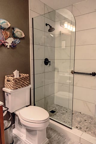 Toilet and walk-in shower with a frameless glass splash guard divider.