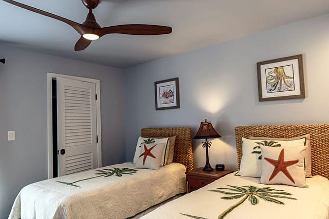Low height ceiling fan with 2 twin beds and seagrass headboards.