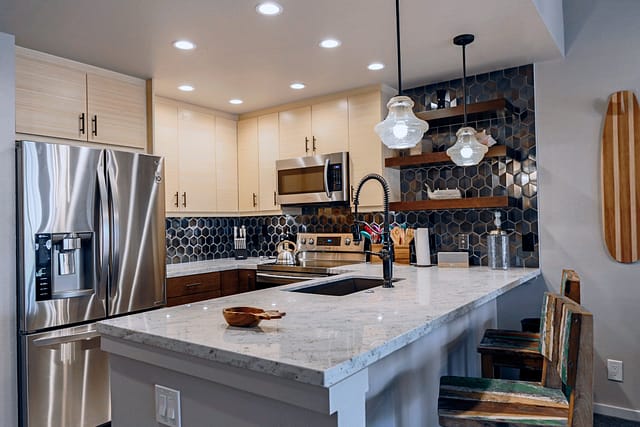U shaped kitchen with stainless steel appliances and 2 bar height stools.