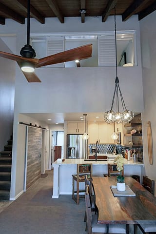 Ceiling fan and large wood dining table in foreground with seating for 4.